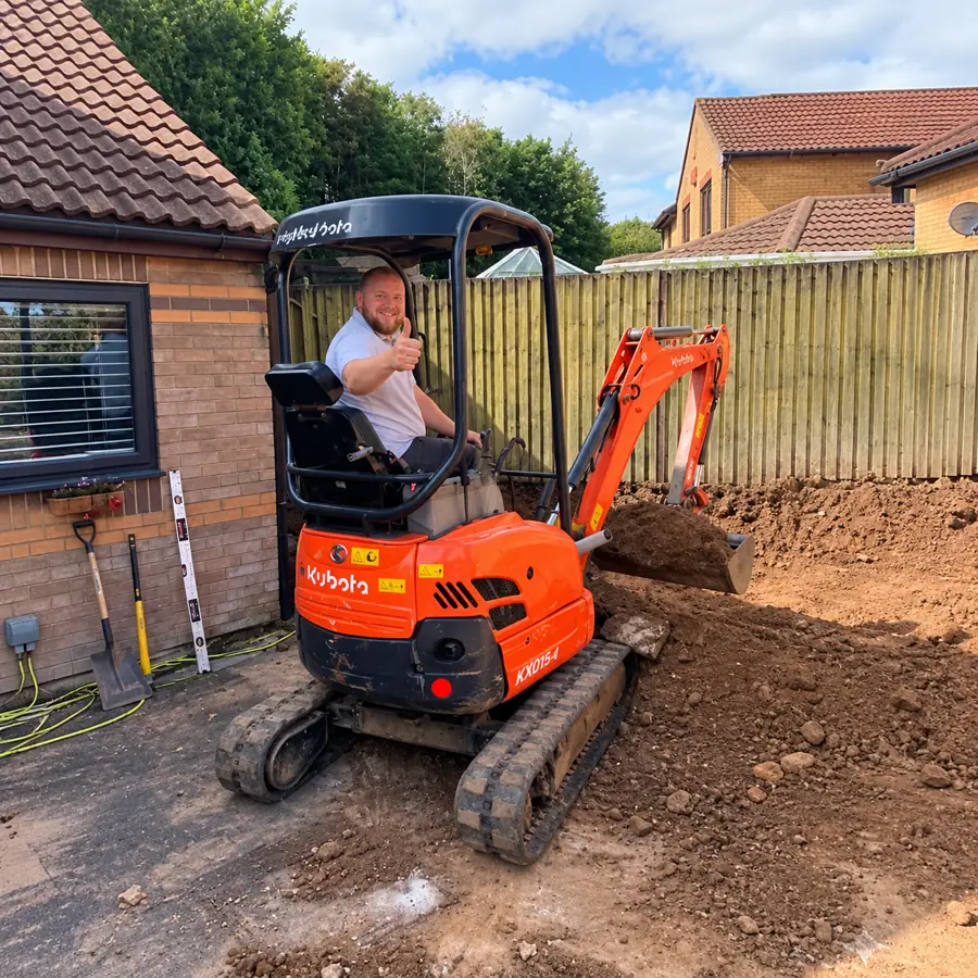 Tom, owner of Ansco Construction, operating a mini digger on a landscaping project